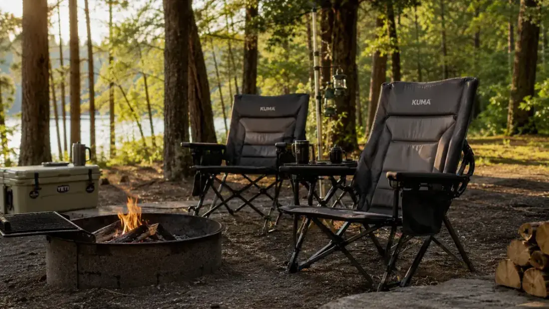 Two oversized heavy duty camping chairs set up around a fire ring at a family campsite in late afternoon light
