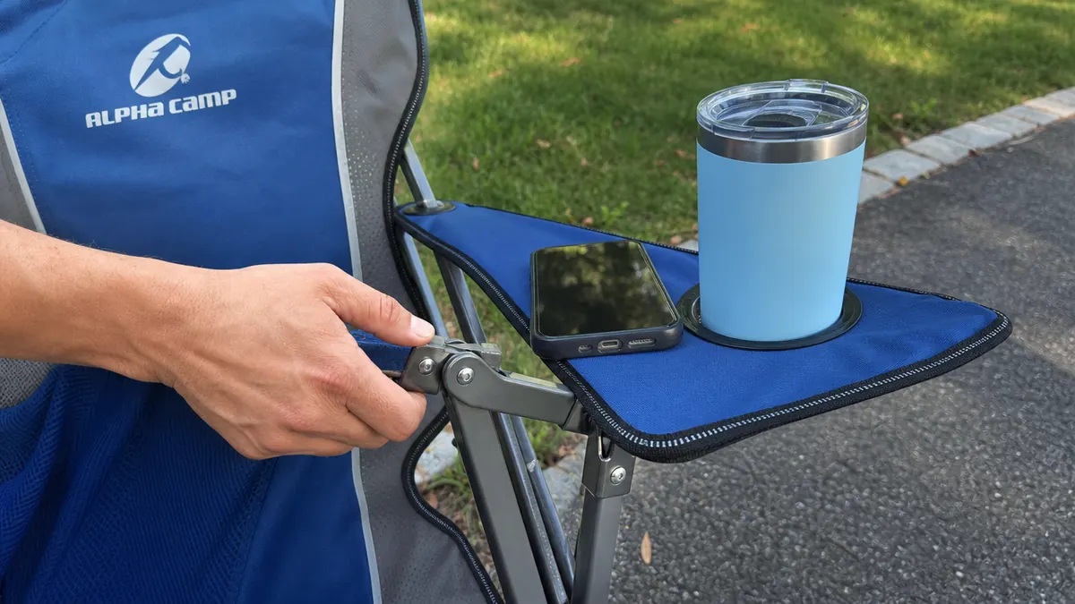 Close-up of hands testing the steel frame hinge and wide padded armrest of a heavy duty camping chair