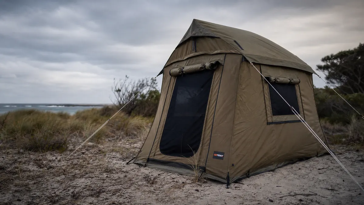Cabin tent pitched at a windy coastal campsite with guylines pulled tight